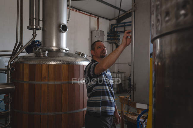 Travailleur masculin faisant fonctionner la machine dans une usine de gin — Photo de stock