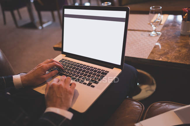 Seção média de homem de negócios usando laptop no bar — Fotografia de Stock