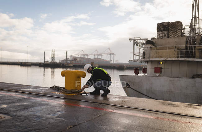 Dock worker tying rope on bollard in the shipyard — Stock Photo