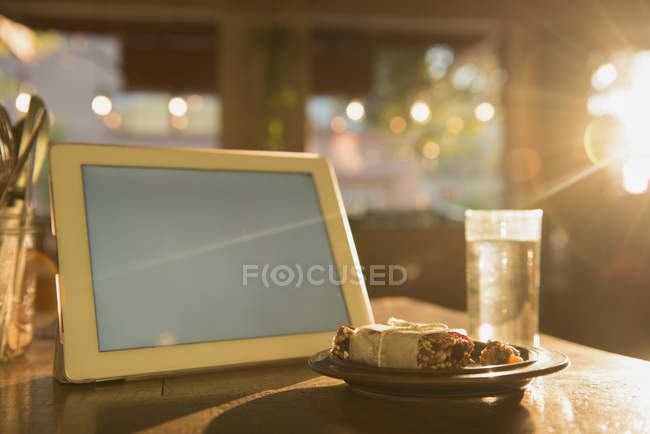 Tableta digital y desayuno en la mesa en la cafetería - foto de stock