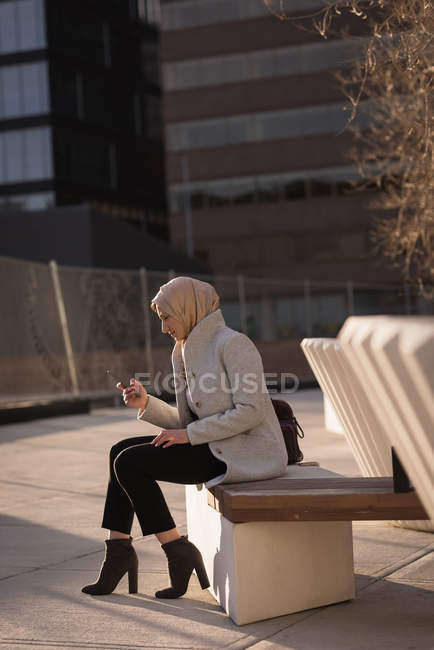 Femme en hijab utilisant un téléphone mobile par une journée ensoleillée — Photo de stock