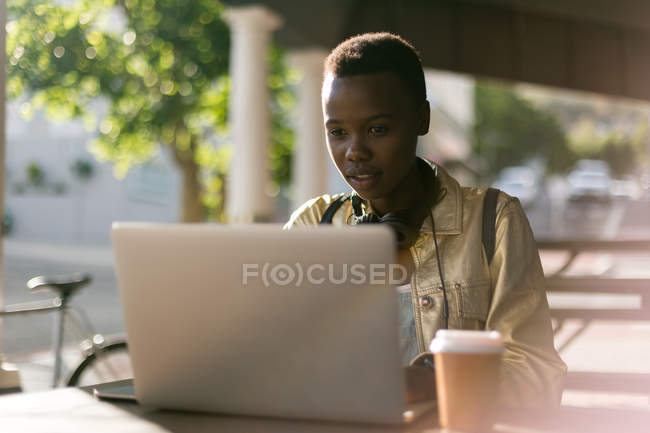 Молода жінка використовує ноутбук у відкритому кафе — стокове фото