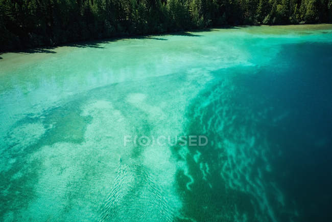 Agua turquesa en las orillas poco profundas a lo largo de la costa en un día soleado - foto de stock