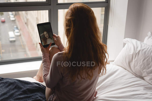 Woman using digital tablet in bedroom at home — Stock Photo