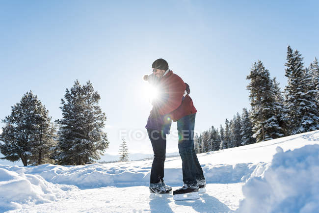 Paar umarmt sich beim Schlittschuhlaufen in verschneiter Landschaft. — Stockfoto
