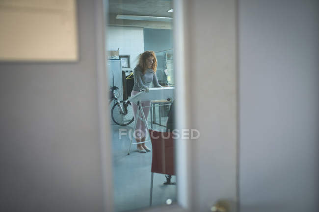 Female executive working over drafting table in office — Stock Photo