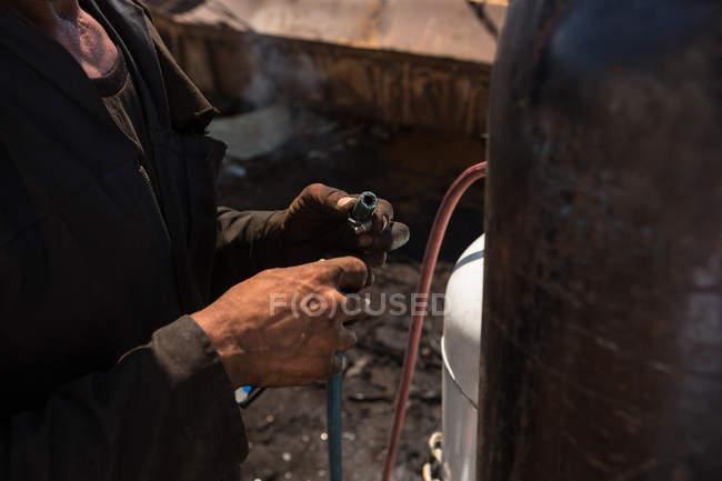 Seção média do trabalhador de pé com um tubo perto do cilindro — Fotografia de Stock