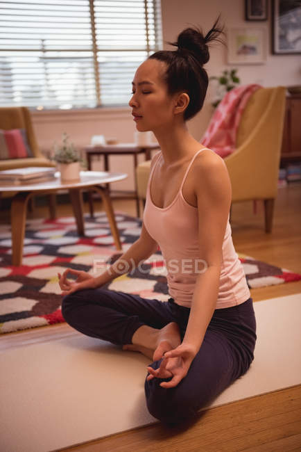 Жінка, що здійснює йога у вітальні на дому — стокове фото