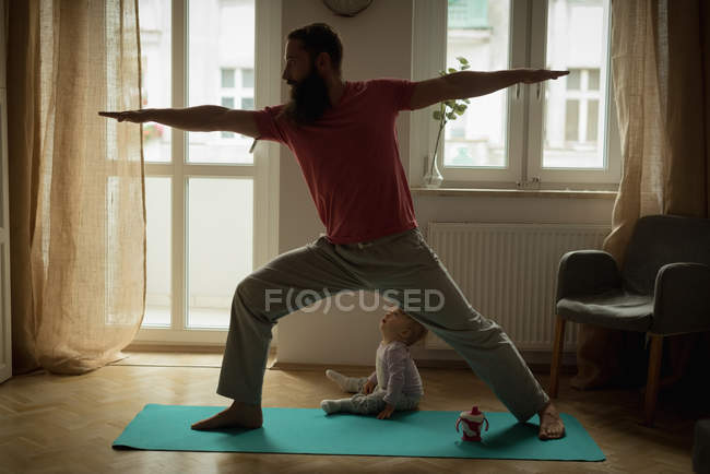 Man performing yoga on exercise mat at home — Stock Photo