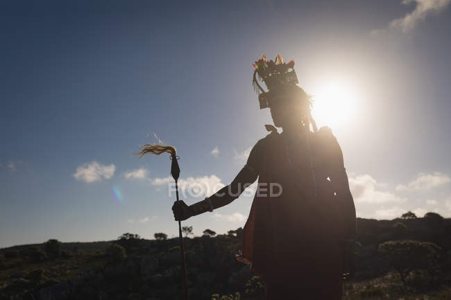 Masaï debout avec un bâton à la campagne par une journée ensoleillée — Photo de stock