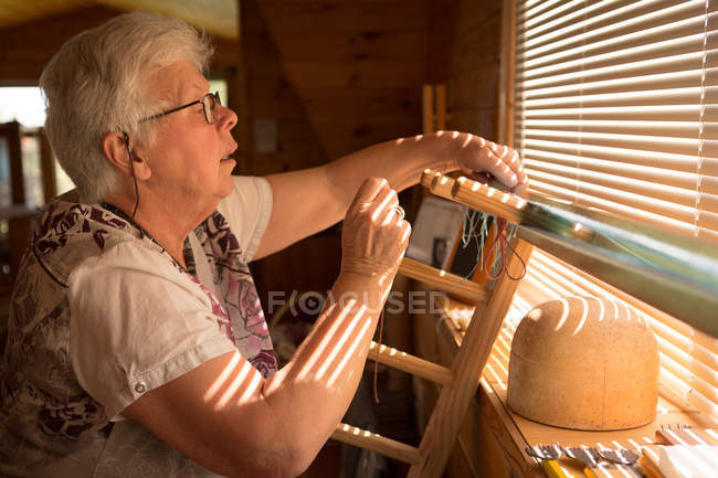 Активная пожилая женщина плетет шелк в магазине — стоковое фото