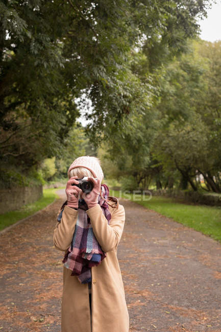 Mulher tirando foto com câmera vintage no parque — Fotografia de Stock