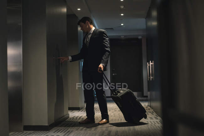 Empresario con bolsa de carro esperando ascensor en hotel - foto de stock