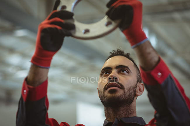 Trabalhador masculino verificando parte da máquina no armazém de fábrica — Fotografia de Stock