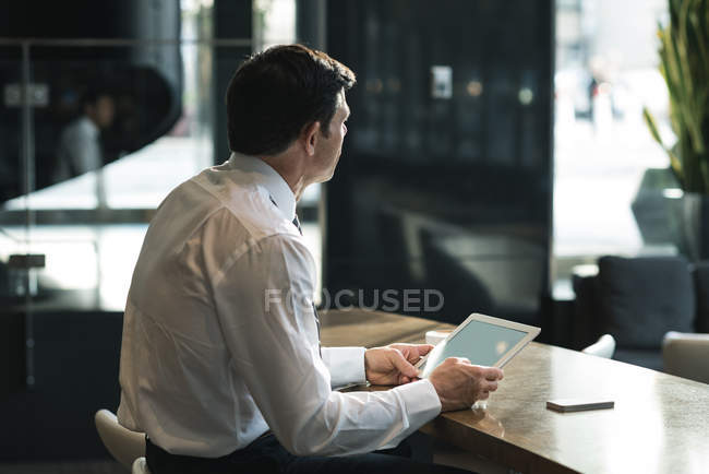 Empresário atencioso usando tablet digital no lobby do escritório — Fotografia de Stock