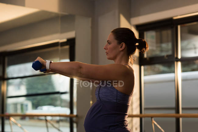 Donna incinta che si allena con i manubri a casa — Foto stock