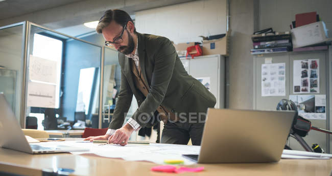 Business executive working on blueprint in office — Stock Photo