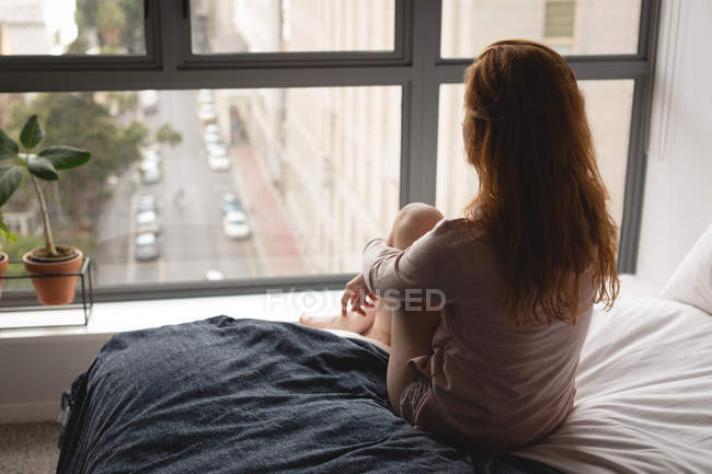 Rückansicht einer Frau, die sich zu Hause im Schlafzimmer entspannt — Stockfoto