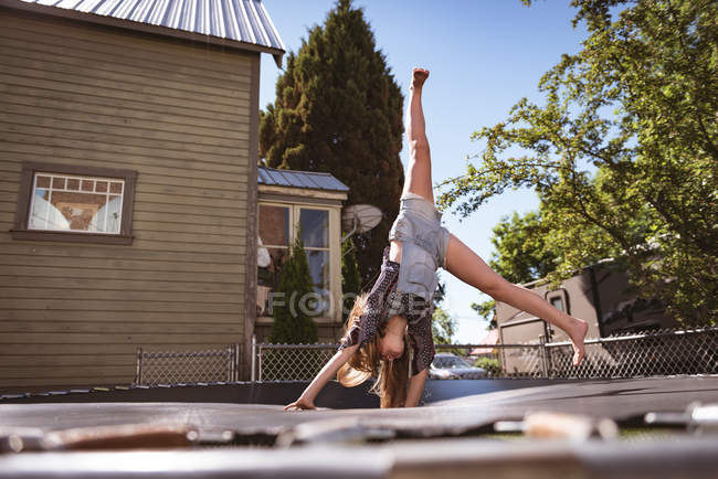 Mädchen springt auf Trampolin in Garten im Grünen. — Stockfoto