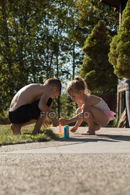 Irmão brincando com varinha de bolha no parque no dia ensolarado — Fotografia de Stock