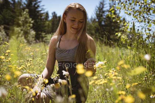 Mädchen berührt Blumen auf Feld im Sommer. — Stockfoto