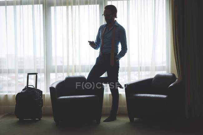 Empresario usando teléfono móvil en habitación de hotel - foto de stock