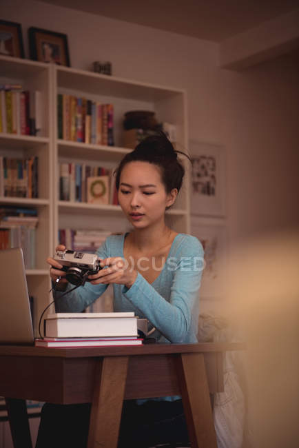 Woman looking at pictures on vintage camera at home — Stock Photo