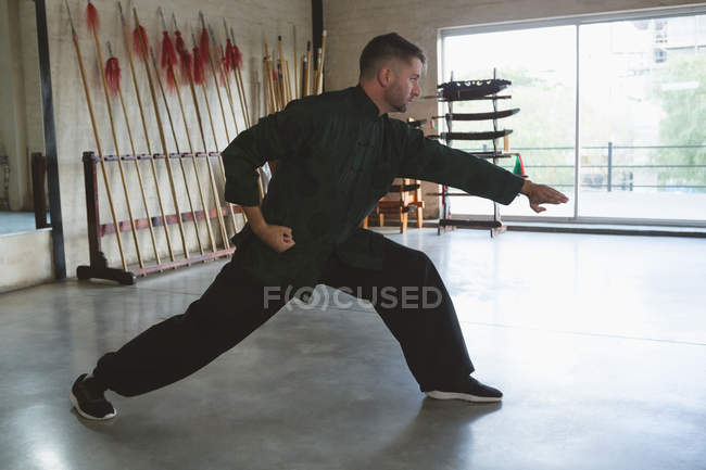 Combattant de kung fu pratiquant les arts martiaux en studio de fitness . — Photo de stock