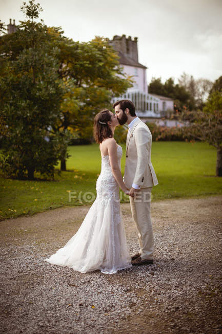 Novia romántica y novio besándose en el jardín - foto de stock