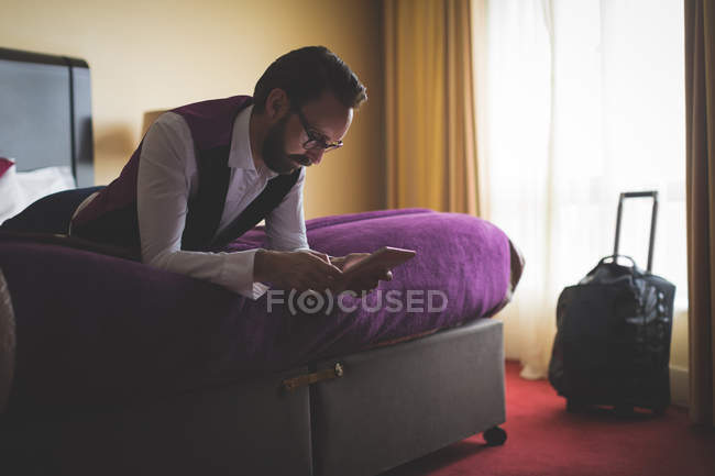 Empresário usando tablet digital na cama do hotel — Fotografia de Stock