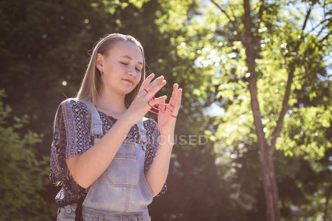 Chica jugando juego de cuerdas con banda de goma en la luz del sol . - foto de stock