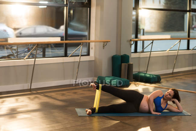 Женщина упражняется с бандажом сопротивления дома — стоковое фото