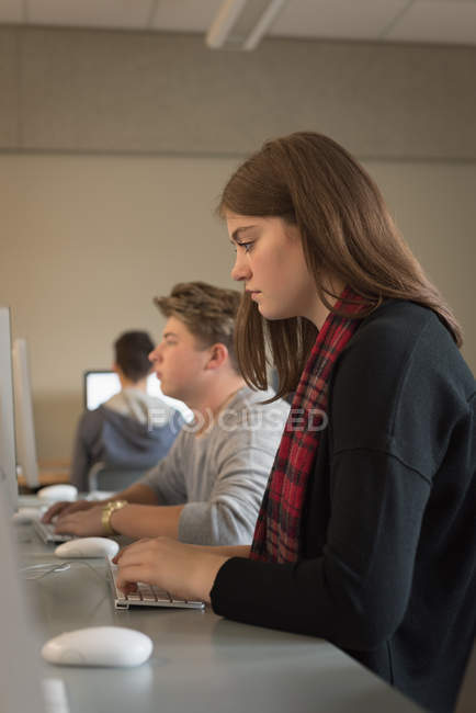 Estudiantes universitarios que estudian en aula de informática en la universidad - foto de stock