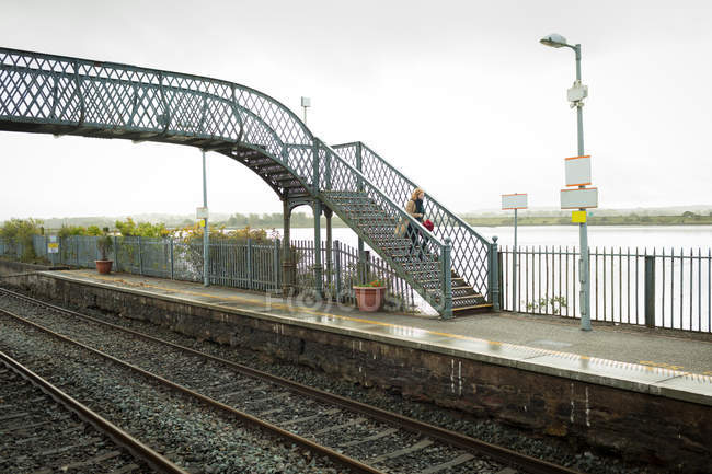 Mulher que desce de uma ponte na estação ferroviária — Fotografia de Stock