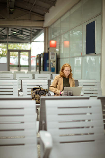 Молода жінка використовує свій ноутбук на автобусній зупинці — стокове фото