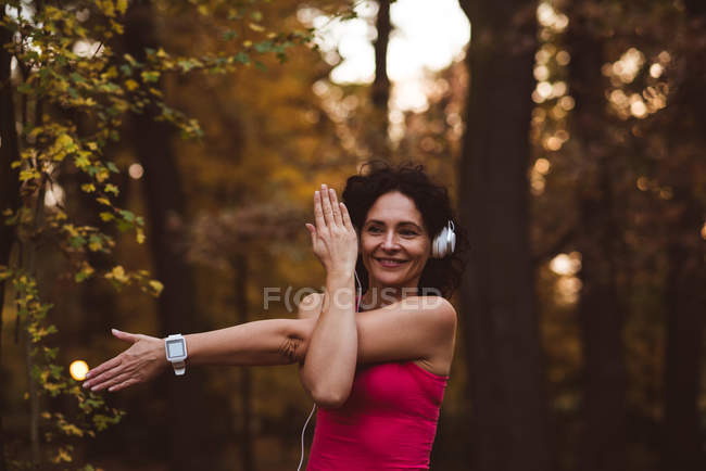 Donna sorridente che esegue esercizio di stretching nella foresta — Foto stock