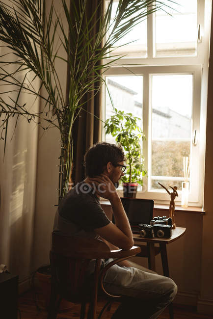Мужчина сидит со старинной камерой за столом в гостиной — стоковое фото