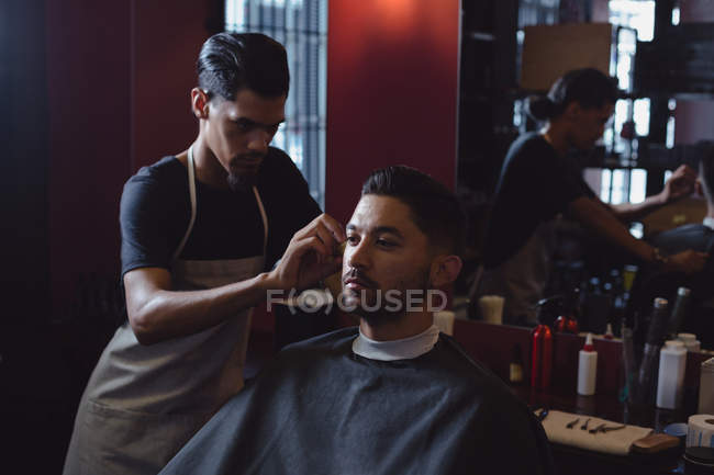 Man getting his hair trimmed with scissor at barbershop — Stock Photo