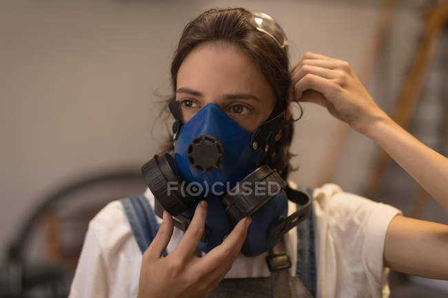 Female artisan wearing gas mask in workshop. — Stock Photo