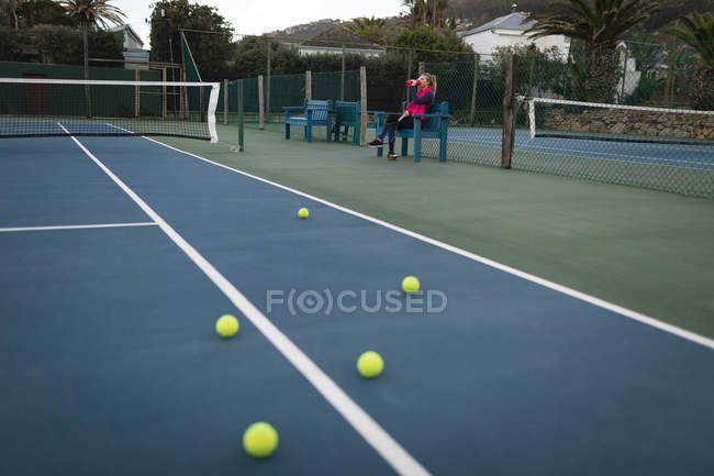 Thirsty woman drinking water in tennis court — Stock Photo