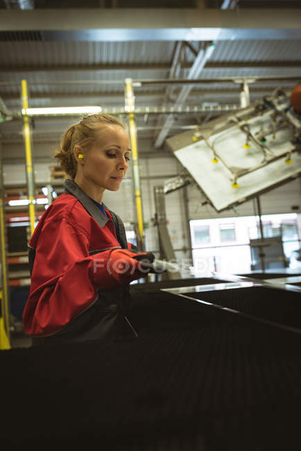 Travailleur féminin vérifiant une feuille de verre dans l'usine — Photo de stock