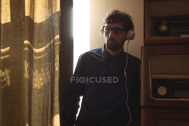 Hombre escuchando música en los auriculares en la sala de estar en casa - foto de stock