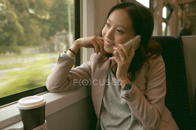 Mulher feliz falando no celular enquanto viaja no trem — Fotografia de Stock