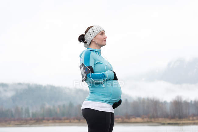 Vista lateral da mulher grávida tocando sua barriga no parque — Fotografia de Stock
