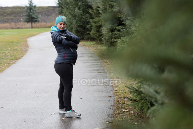 Mujer embarazada usando teléfono móvil en el parque - foto de stock
