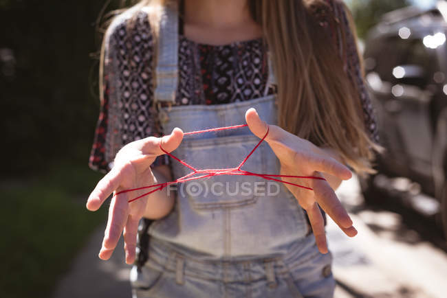 Partie médiane de la fille jouant à un jeu de cordes avec les mains . — Photo de stock
