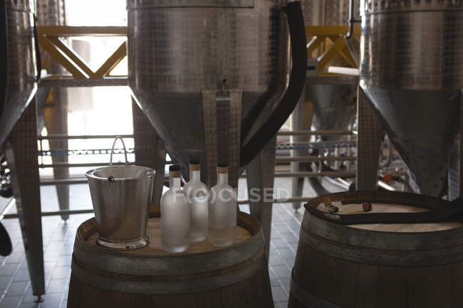 Eimer und Gin-Flasche auf Fass in Fabrik — Stockfoto