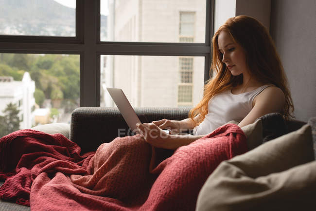 Молода жінка користується ноутбуком вдома. — стокове фото