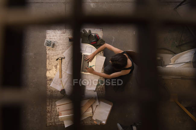 Vista aérea de la mujer artesana usando portátil en el taller . - foto de stock