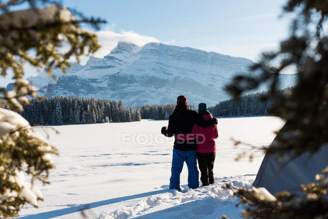 Paar steht im Winter gemeinsam in Berglandschaft. — Stockfoto